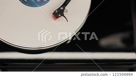 Male hands operating vinyl record player with a vinyl disc. The needle rises from a vintage vinyl record. The vinyl record is spinning. 121504994
