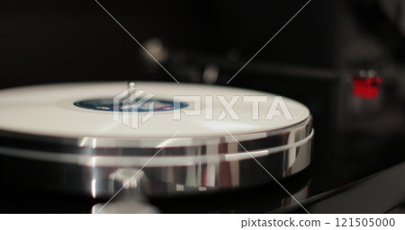 Man places a white disk on a vinyl player. Vinyl record gets placed on a turntable. Classic vinyl record player. 121505000