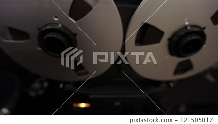 Bobbin tape recorder. Old vintage reel-to-reel player. Vintage tape recorder roller. Reel film tape is rotating at a vintage professional player. Bobbin tape recorder. Old vintage reel-to-reel player. Vintage tape recorder roller. Reel film tape is rotating at a vintage professional player. 121505017