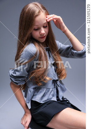 A Stylish Girl in a Gray Cardigan is Posing Gracefully for the Camera in a Studio Setting 121505270