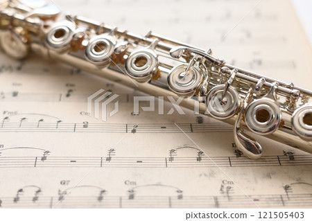 一根銀笛，上面有一把環形鑰匙，放在舊樂譜上 121505403