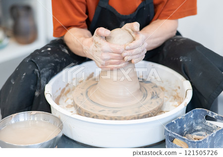 Close-up of a potter's hands working on a pottery wheel. Close-up of a potter's hands working on a pottery wheel. 121505726