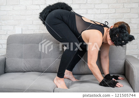 Caucasian woman in cat costume sits on gray sofa. Quadrober. Caucasian woman in cat costume sits on gray sofa. Quadrober. 121505744