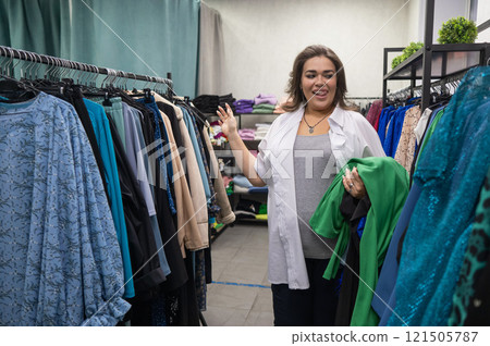 A fat woman chooses clothes in a plus size store.  121505787