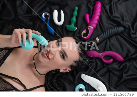 Portrait of Caucasian woman lying on bed among sex toys. Portrait of Caucasian woman lying on bed among sex toys. 121505789