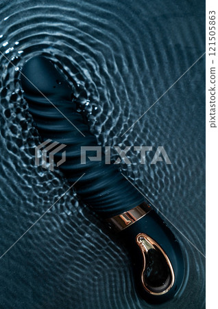 Black silicone vibrator in water. Circles on water around sex toy.  121505863