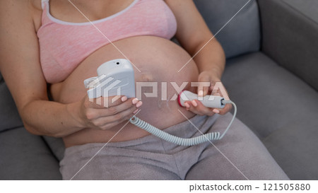 Close-up of a pregnant woman's belly using a home doppler. Normal baby heartbeat. Close-up of a pregnant woman's belly using a home doppler. Normal baby heartbeat. 121505880