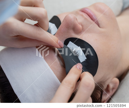 The master applies protective patches that do not let in ultraviolet rays before LED eyelash extensions.  121505894