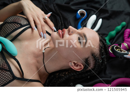 Portrait of Caucasian woman lying on bed among sex toys.  121505945