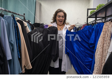 A fat woman chooses clothes in a plus size store. A fat woman chooses clothes in a plus size store. 121505959