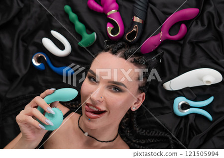 Portrait of Caucasian woman lying on bed among sex toys. Portrait of Caucasian woman lying on bed among sex toys. 121505994