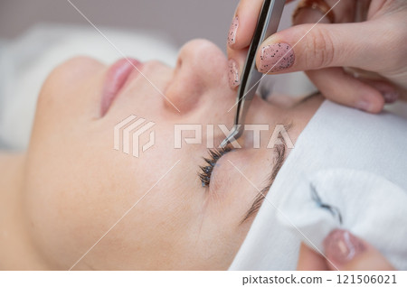 A master removes eyelash extensions from a client. 121506021