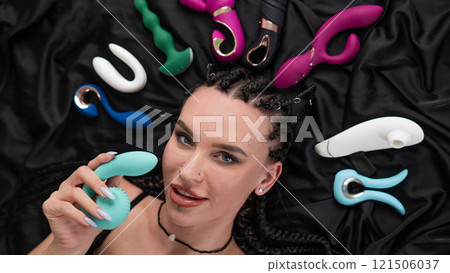 Portrait of Caucasian woman lying on bed among sex toys.  121506037