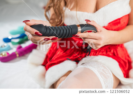 Caucasian woman in santa claus costume and stockings lies on bed with sex toy.  121506052