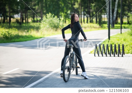 Rear view of Caucasian woman riding bike in park. Rear view of Caucasian woman riding bike in park. 121506103