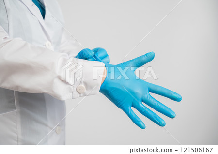 The doctor puts on latex gloves on a white background. The doctor puts on latex gloves on a white background. 121506167