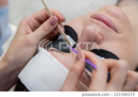 The master cleans the client's eyelashes from sebum before extensions. The master cleans the client's eyelashes from sebum before extensions. 121506173