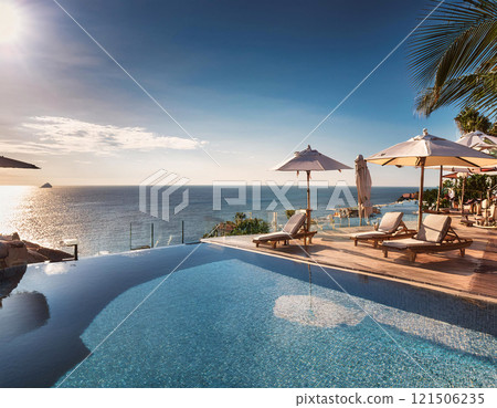 A serene infinity pool with lounge chairs and umbrellas overlooks a vast ocean under a partly cloudy sky 121506235