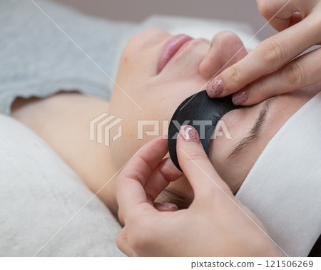 The master applies protective patches that do not let in ultraviolet rays before LED eyelash extensions. The master applies protective patches that do not let in ultraviolet rays before LED eyelash extensions. 121506269