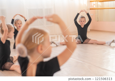 Little girls sit in a circle and do stretching at a ballet school. Little girls sit in a circle and do stretching at a ballet school. 121506313