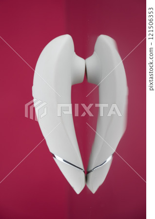 Clitoral vibrator on mirrored pink surface.  121506353