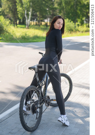 Rear view of Caucasian woman riding bike in park. Vertical photo. Rear view of Caucasian woman riding bike in park. Vertical photo. 121506413