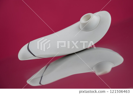 Clitoral vibrator on mirrored pink surface.  121506463
