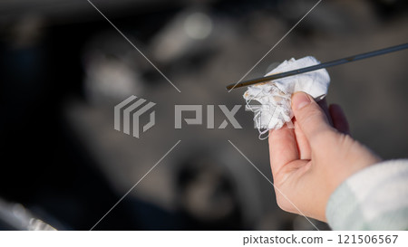 Close up of hands of female driver checking oil level in car engine. Close up of hands of female driver checking oil level in car engine. 121506567