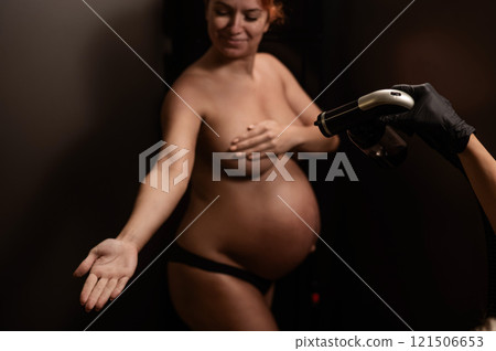 The master applies bronzer with a spray on the hands of a pregnant woman. Instant tan. The master applies bronzer with a spray on the hands of a pregnant woman. Instant tan. 121506653