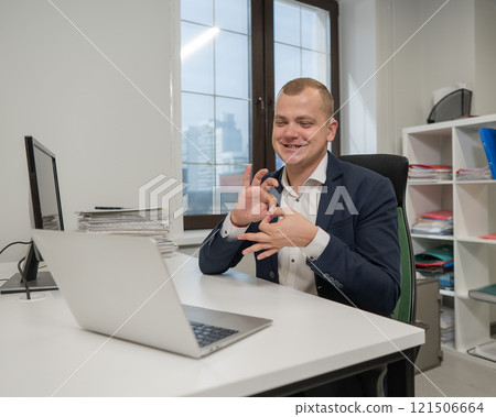 Caucasian deaf man talking sign language over video call on laptop in office. 121506664