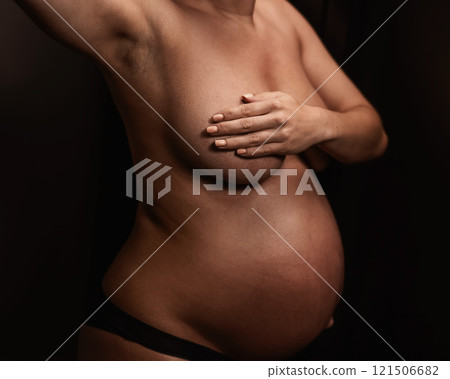 Faceless pregnant woman getting an instant tan. The master applies bronzer with a spray. 121506682