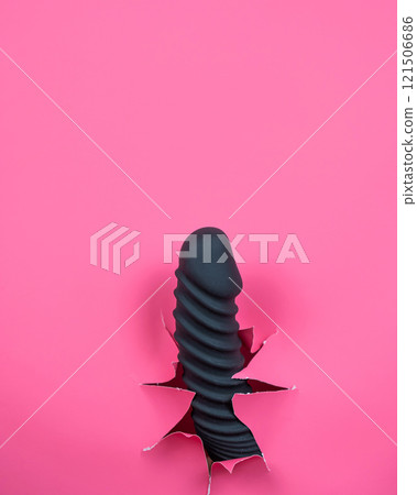 Black ribbed dildo sticking out of hole on pink background. Vertical video.  121506686