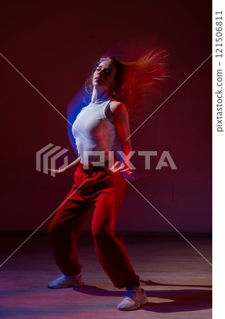 A young woman dances contemporary dances in blue and red light. Long exposure. Vertical photo.  121506811