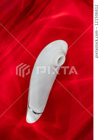 Clitoral vibrator in highlights on red background.  121506812