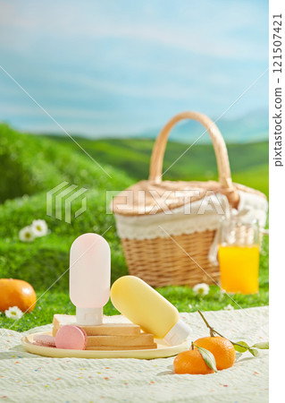 A spring picnic takes place on a green lawn, food and drink scattered arranged on a white picnic carpet with some unbranded sunscreen bottle displayed in center. Background of green hill and blue sky A spring picnic takes place on a green lawn, food and drink scattered arranged on a white picnic carpet with some unbranded sunscreen bottle displayed in center. Background of green hill and blue sky 121507421