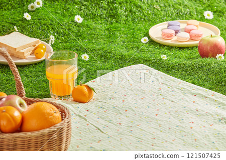 Outdoor picnic set up on green lawn photo with many sunshine in spring time. Picnic carpet was spread on green grass, features some food and drink, blank space for product displaying Outdoor picnic set up on green lawn photo with many sunshine in spring time. Picnic carpet was spread on green grass, features some food and drink, blank space for product displaying 121507425