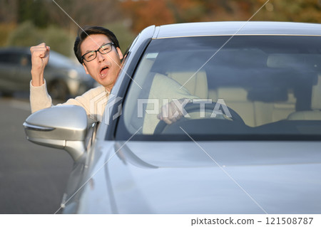 Middle-aged man getting irritated while driving 121508787