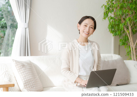 Woman working on a computer on the sofa Woman working on a computer on the sofa 121509433