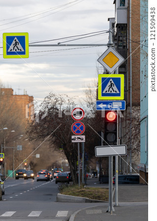 Pedestrian crossing signs on a traffic light stand at an intersection. 121509438