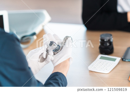 一個不露面的年輕人正在從買家那裡得到他放在家裡的一塊手錶的估價。 一個不露面的年輕人正在從買家那裡得到他放在家裡的一塊手錶的估價。 121509819