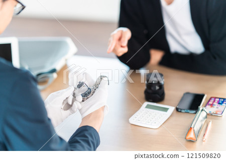 A young man, no face, getting an estimate from a buyer for a watch he had stored at home A young man, no face, getting an estimate from a buyer for a watch he had stored at home 121509820