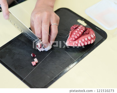 Man's hands cutting octopus - food preparation scene 121510273
