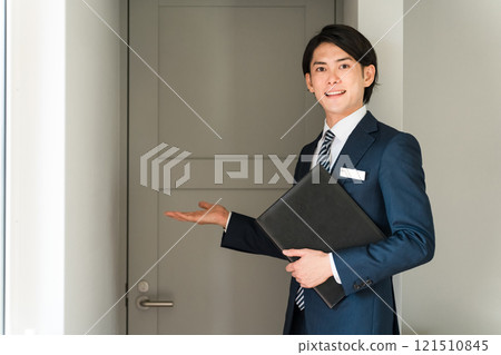 A male advisor/planner from a house manufacturer showing a model house/model room A male advisor/planner from a house manufacturer showing a model house/model room 121510845