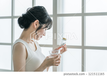 Asian woman with headache and feeling unwell taking medicine (troubled, worried) 121511165