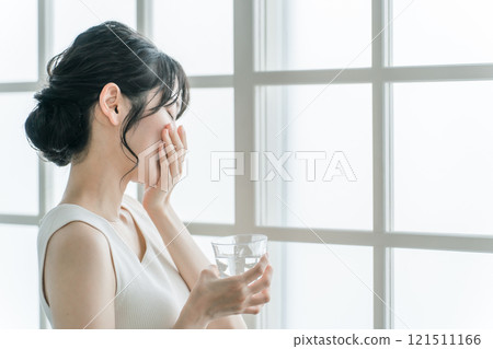 Asian woman with headache and feeling unwell taking medicine 121511166