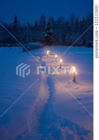 A Serene Winter Pathway That is Beautifully Illuminated by Lanterns Shining in the Snow 121511692
