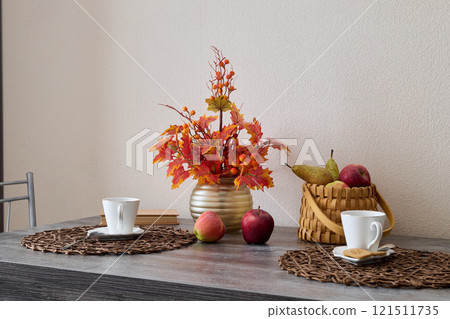 A Cozy Autumn Table Setting Featuring Beautiful Fruit and Decorative Flowers for Enjoyment 121511735