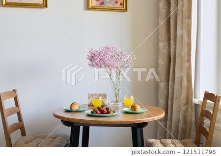 Charming and Inviting Breakfast Table Setup Featuring Fresh Fruits and Beautiful Flowers 121511798
