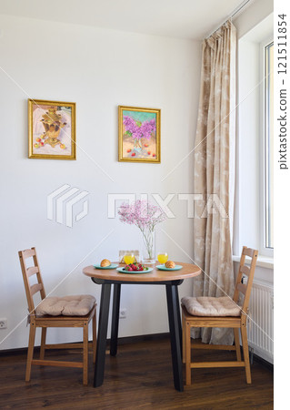 A Cozy Dining Space Featuring Beautiful Floral Decor and Vibrant Colorful Artwork A Cozy Dining Space Featuring Beautiful Floral Decor and Vibrant Colorful Artwork 121511854