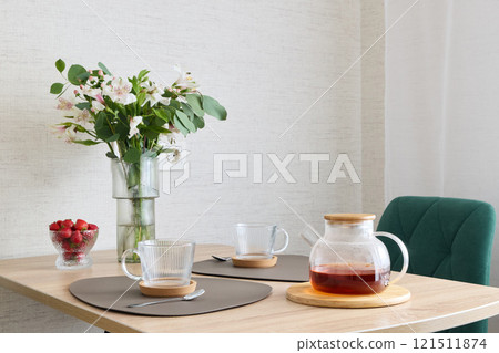 A Cozy and Inviting Dining Table Setup Featuring Tea and Fresh Flowers for Decoration 121511874